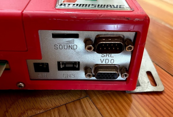 Atomiswave ports adjacent to the JAMMA connector: Serial, 15-pin VGA, a few dip switches, a volume wheel, and a 'CN3' port